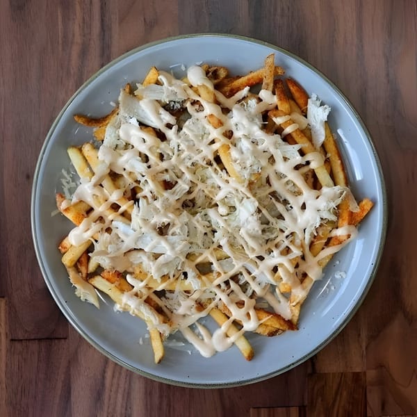 Roostr Yard's crispy fries topped with shredded grilled chicken and a creamy white sauce.