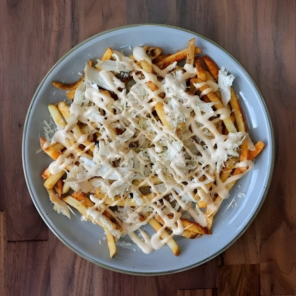 Roostr Yard's crispy fries topped with shredded grilled chicken and a creamy white sauce.